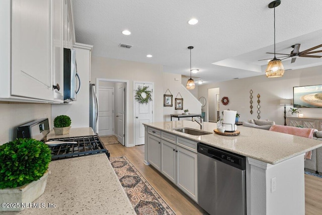 kitchen with a center island with sink, appliances with stainless steel finishes, sink, decorative light fixtures, and white cabinets