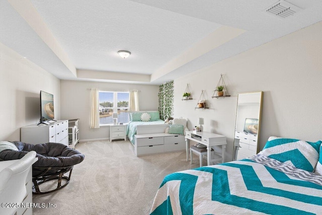 bedroom featuring light carpet and a tray ceiling