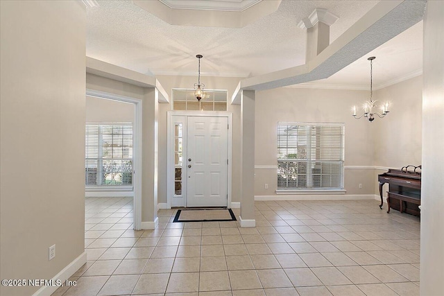 tiled entrance foyer featuring ornamental molding, a textured ceiling, and a chandelier