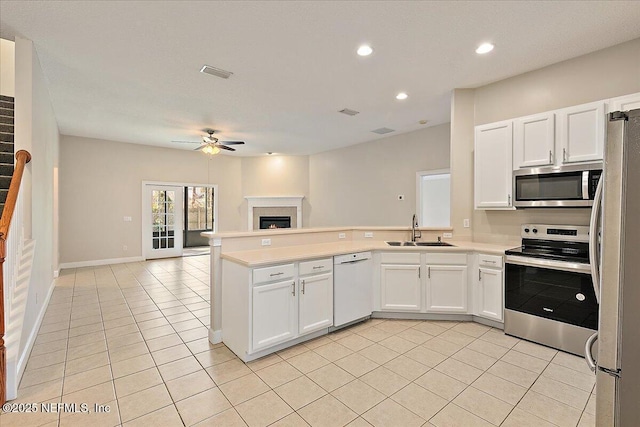 kitchen featuring light tile patterned flooring, sink, white cabinetry, appliances with stainless steel finishes, and kitchen peninsula