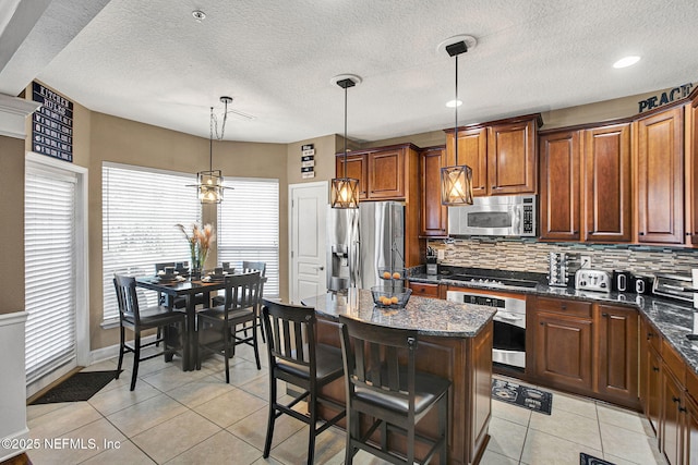 kitchen featuring pendant lighting, a breakfast bar area, stainless steel appliances, a kitchen island, and decorative backsplash