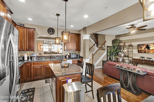 kitchen featuring sink, stainless steel fridge, backsplash, a center island, and decorative light fixtures