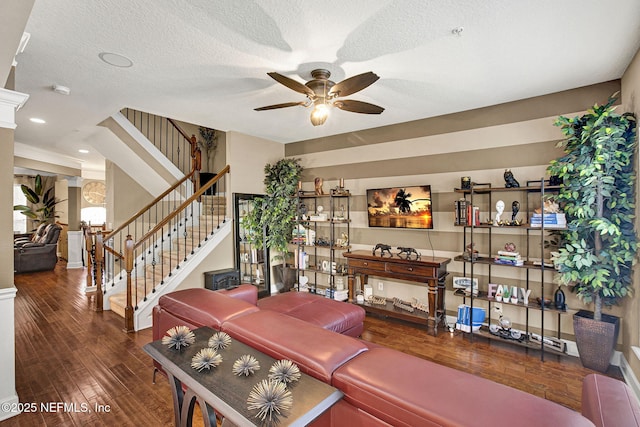 living room featuring ceiling fan, dark wood-type flooring, and a textured ceiling