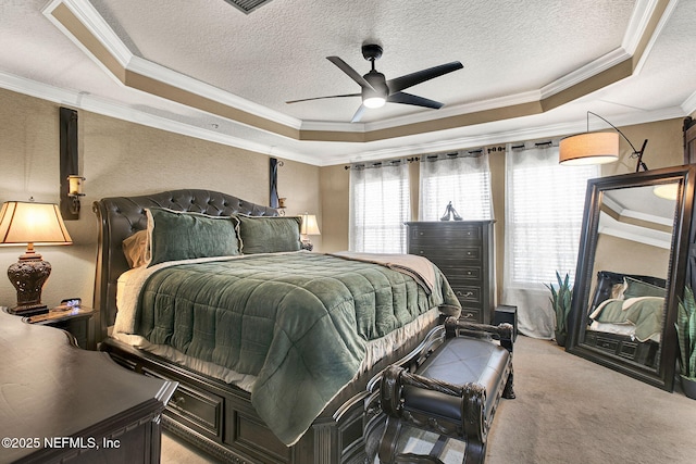 carpeted bedroom with ornamental molding, a raised ceiling, and a textured ceiling