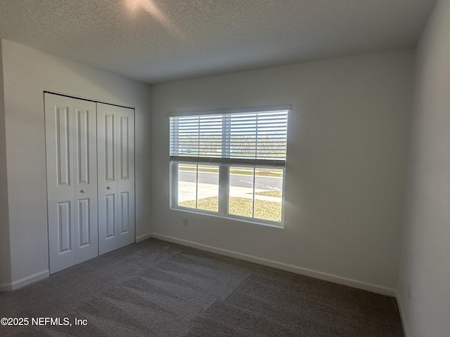 unfurnished bedroom featuring a closet, baseboards, a textured ceiling, and carpet