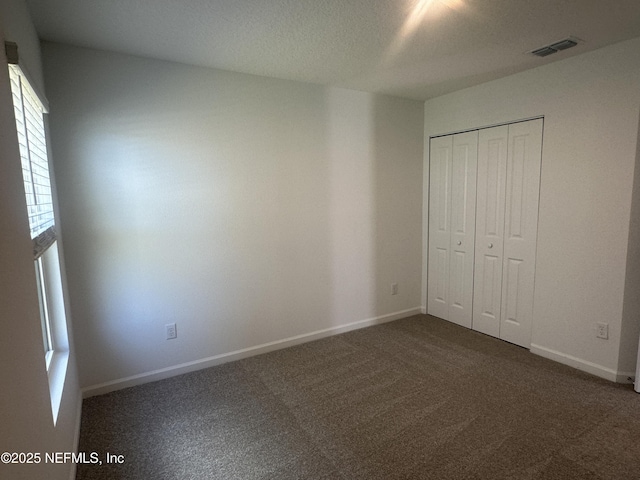 unfurnished bedroom with a closet, carpet flooring, baseboards, and visible vents