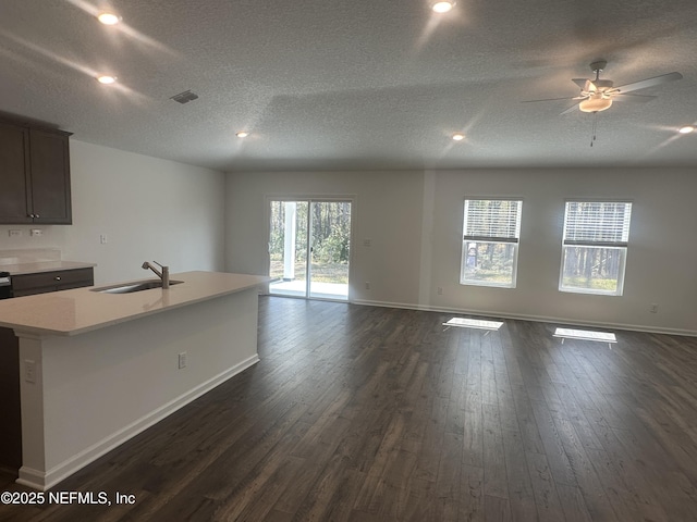 kitchen with dark wood-type flooring, light countertops, open floor plan, and a sink