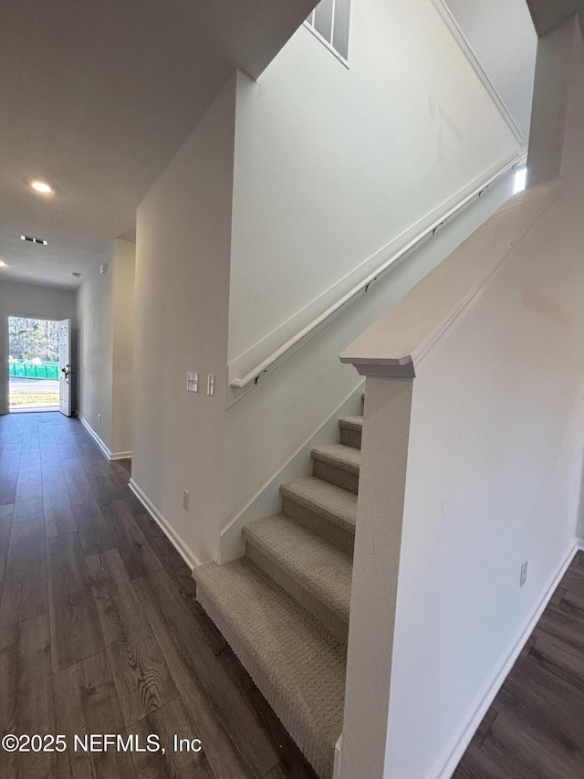 staircase with wood finished floors, visible vents, and baseboards