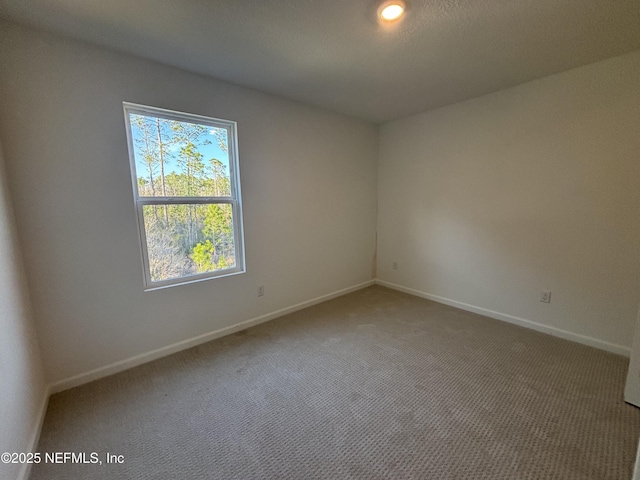 carpeted empty room featuring baseboards