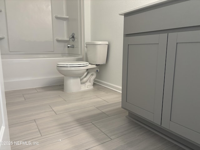 bathroom with shower / tub combination, toilet, and baseboards