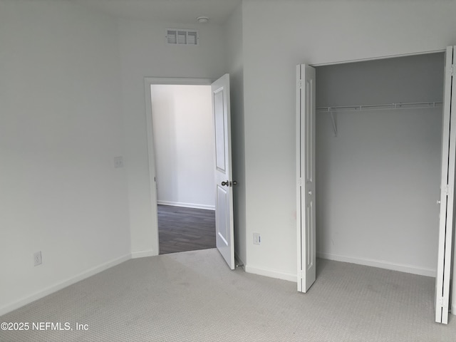 unfurnished bedroom with a closet, carpet, visible vents, and baseboards