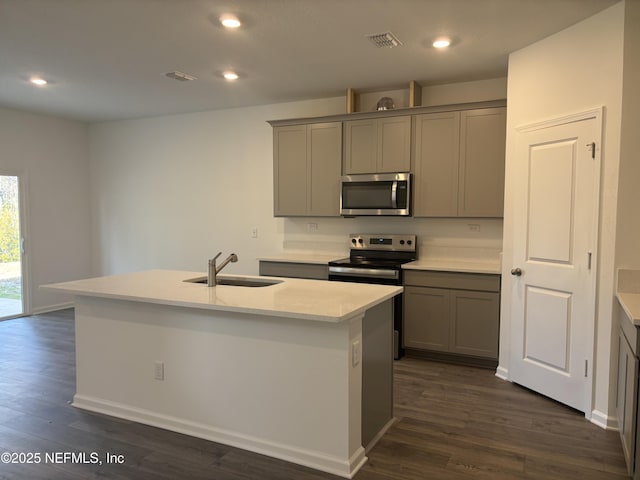 kitchen with visible vents, dark wood-style floors, gray cabinets, stainless steel appliances, and a sink