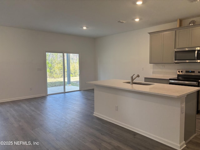 kitchen with a center island with sink, dark wood-style flooring, gray cabinets, stainless steel appliances, and a sink