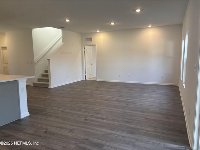 empty room featuring baseboards, visible vents, dark wood-type flooring, stairs, and recessed lighting