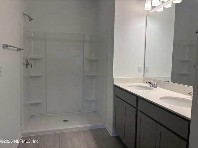 full bath with a shower, double vanity, and a sink