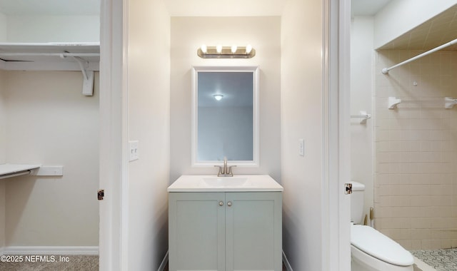 bathroom featuring vanity, toilet, and a tile shower