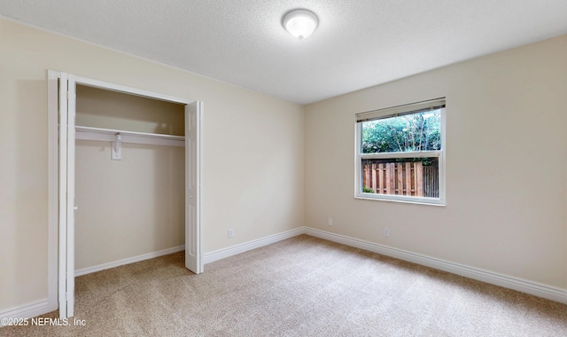 unfurnished bedroom with a closet, light carpet, and a textured ceiling