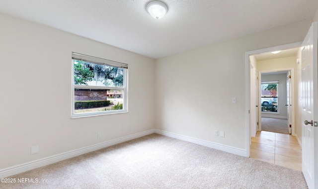 empty room with light colored carpet and a textured ceiling