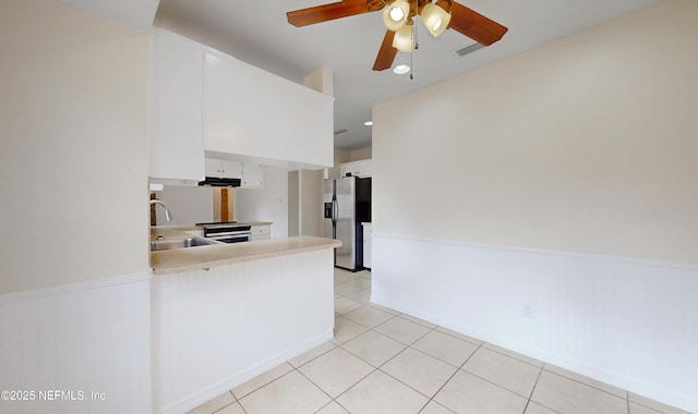 kitchen featuring appliances with stainless steel finishes, white cabinetry, sink, light tile patterned floors, and kitchen peninsula