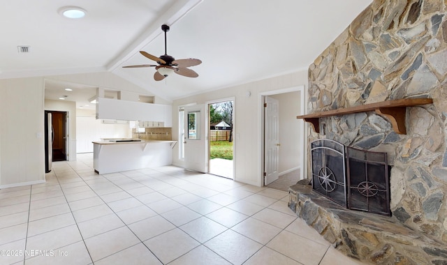 unfurnished living room featuring a stone fireplace, lofted ceiling with beams, ceiling fan, and light tile patterned flooring