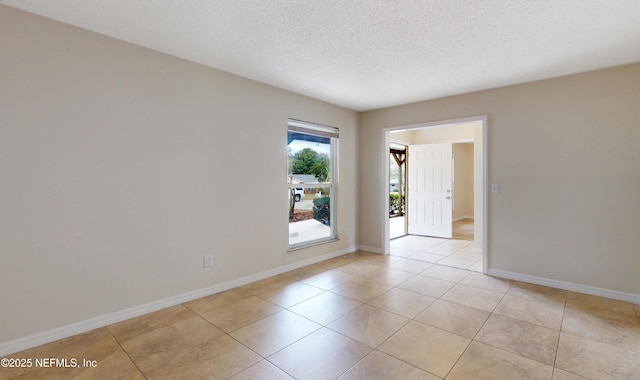 tiled empty room featuring a textured ceiling