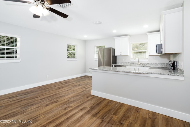 kitchen with sink, stainless steel appliances, light stone counters, white cabinets, and kitchen peninsula