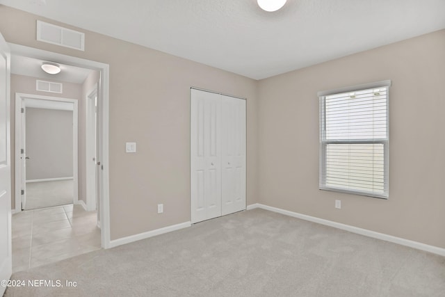 unfurnished bedroom with light carpet and a closet