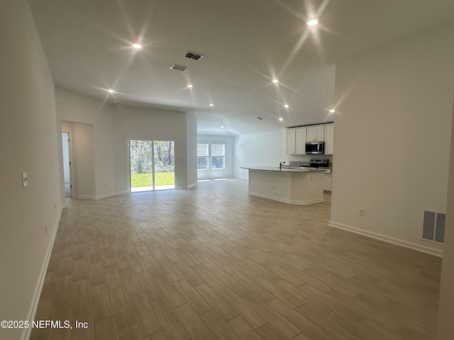 unfurnished living room with light wood-style flooring, baseboards, and visible vents