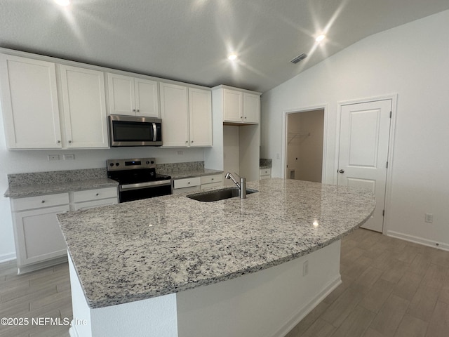 kitchen with visible vents, a sink, vaulted ceiling, appliances with stainless steel finishes, and white cabinetry