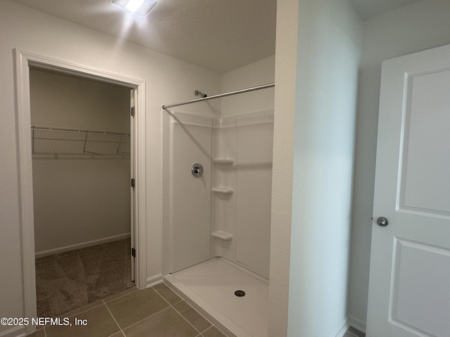 full bath featuring tile patterned floors, a walk in closet, visible vents, and a stall shower