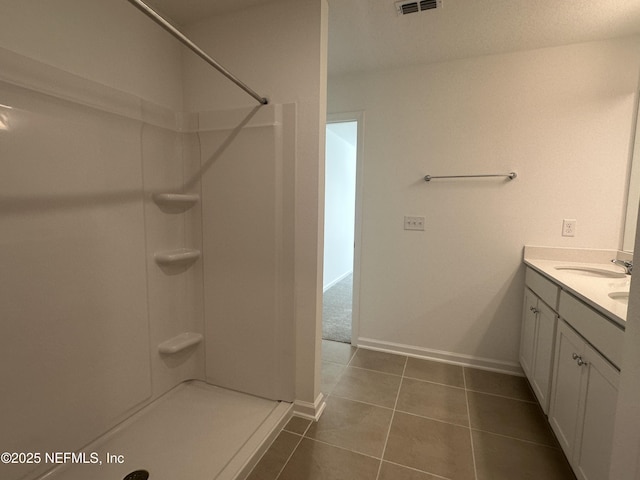 bathroom featuring visible vents, tile patterned flooring, baseboards, walk in shower, and vanity