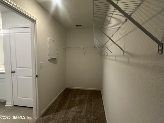 walk in closet with electric panel, visible vents, carpet floors, and tile patterned flooring