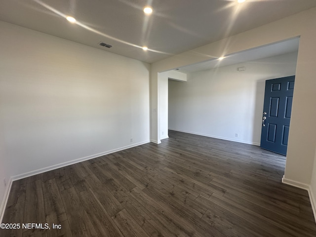 unfurnished room featuring dark wood-type flooring, baseboards, and visible vents