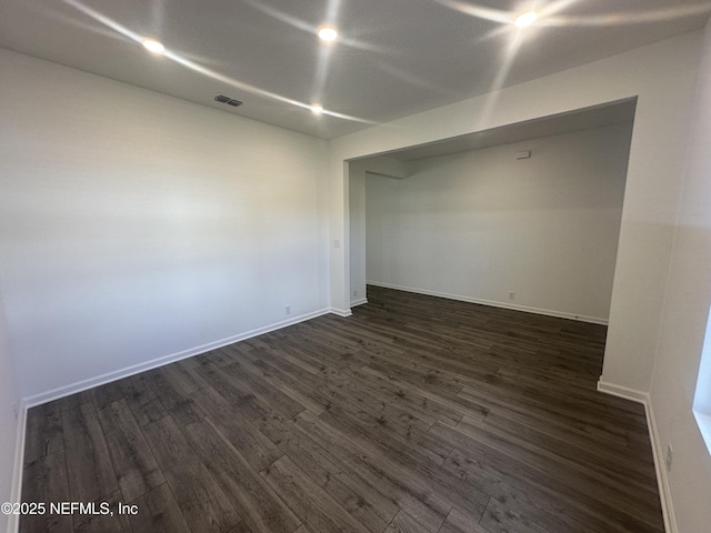 unfurnished room with dark wood finished floors, visible vents, and baseboards