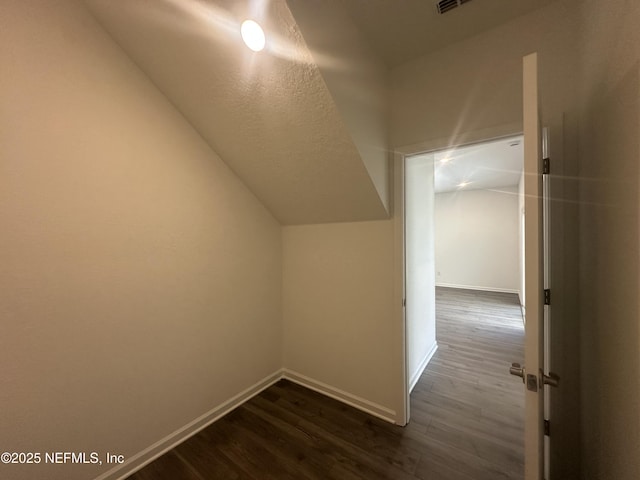 bonus room featuring baseboards, dark wood-style flooring, and vaulted ceiling