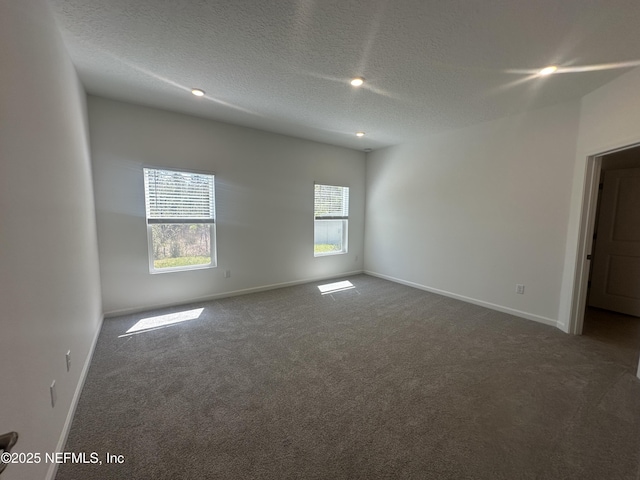 carpeted empty room with a textured ceiling and baseboards