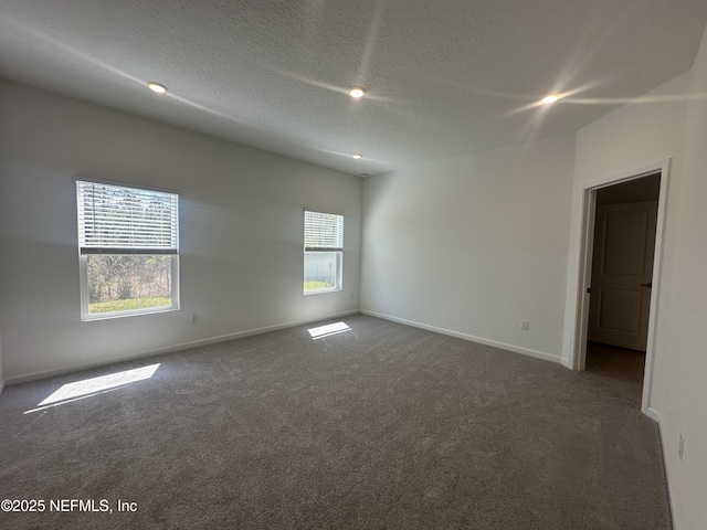 unfurnished room featuring a textured ceiling, baseboards, and dark colored carpet