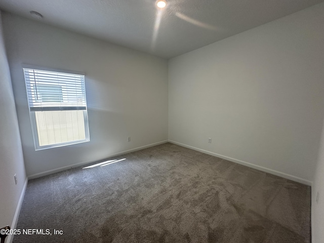 empty room featuring carpet flooring and baseboards