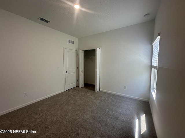 unfurnished bedroom with visible vents, baseboards, carpet, and a textured ceiling