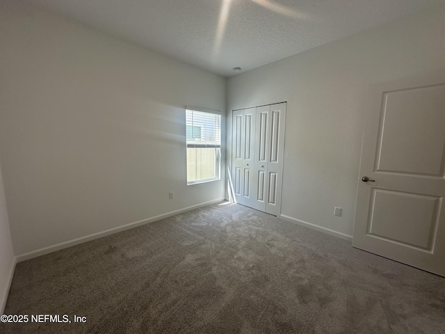 unfurnished bedroom featuring baseboards, a closet, a textured ceiling, and carpet