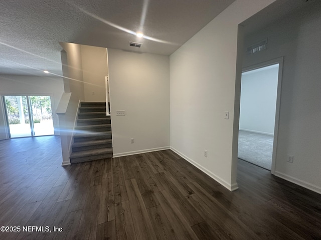 interior space featuring visible vents, baseboards, dark wood finished floors, stairs, and a textured ceiling