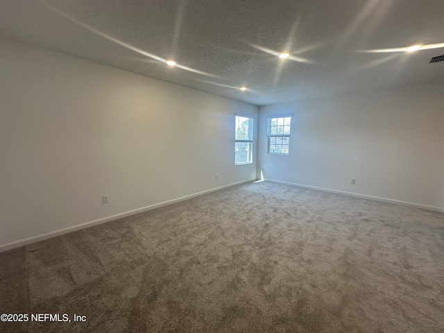 empty room featuring visible vents, carpet, baseboards, and a textured ceiling