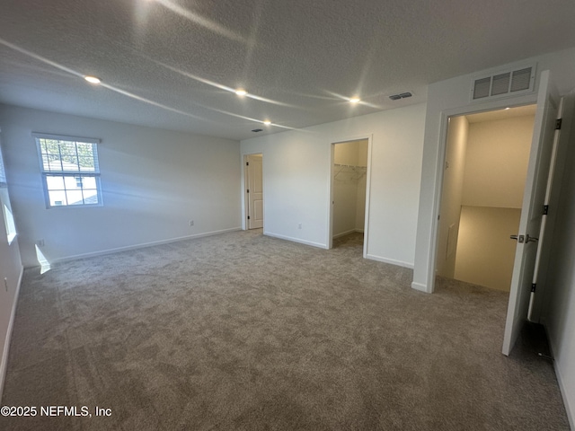 unfurnished bedroom with visible vents, carpet flooring, a textured ceiling, and baseboards