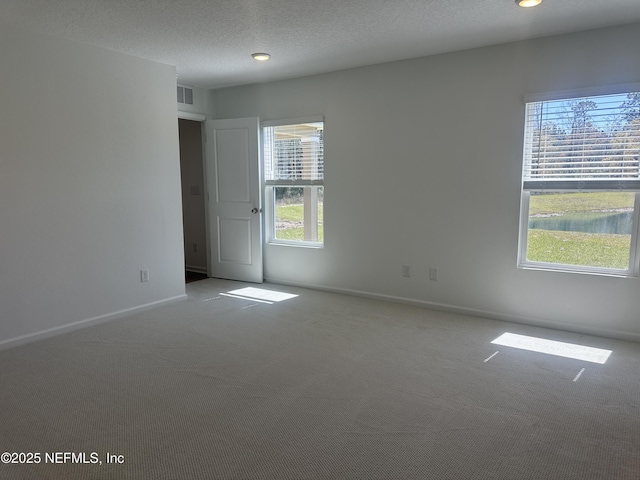 carpeted empty room with baseboards, visible vents, and a textured ceiling