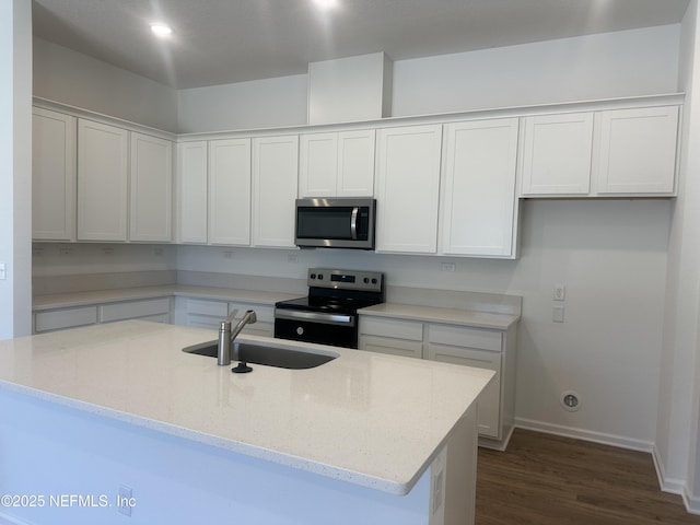 kitchen featuring white cabinets, light stone counters, appliances with stainless steel finishes, and a sink