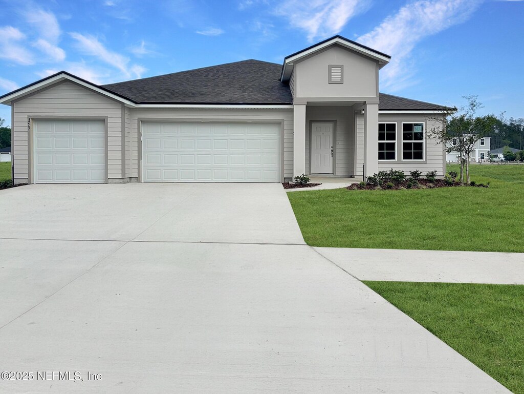 view of front of property with a shingled roof, a garage, a front yard, and concrete driveway