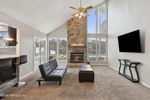 carpeted living room featuring ceiling fan, a stone fireplace, high vaulted ceiling, and a healthy amount of sunlight