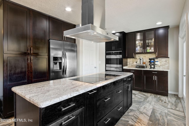 kitchen with island range hood, dark brown cabinets, appliances with stainless steel finishes, a kitchen island, and backsplash