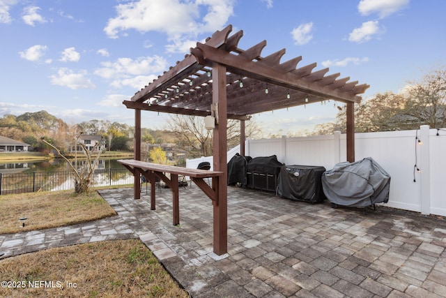 view of patio with area for grilling, a pergola, and a water view