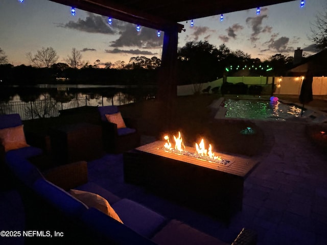 patio terrace at dusk featuring an outdoor living space with a fire pit and a water view